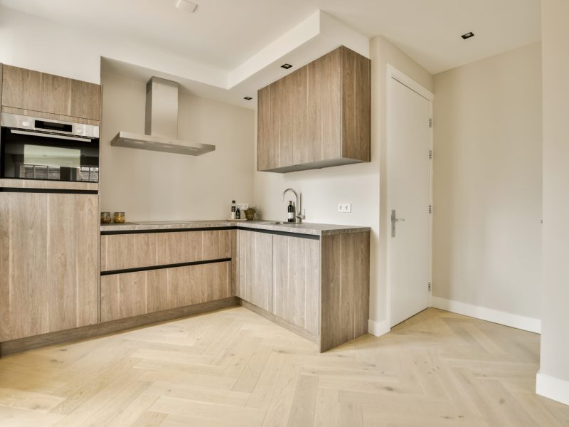 a modern kitchen with wood flooring and white walls in the room is very clean, ready for guests to use