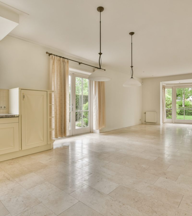 Interior of spacious light room with fireplace against door and windows