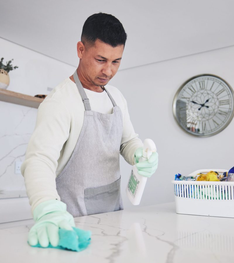 Man, housekeeper and cleaning table in kitchen, hygiene or germ and bacteria removal at home. Male .