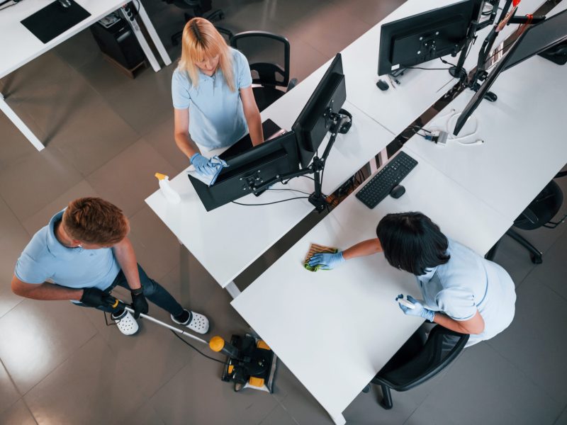 Top view. Group of workers clean modern office together at daytime.